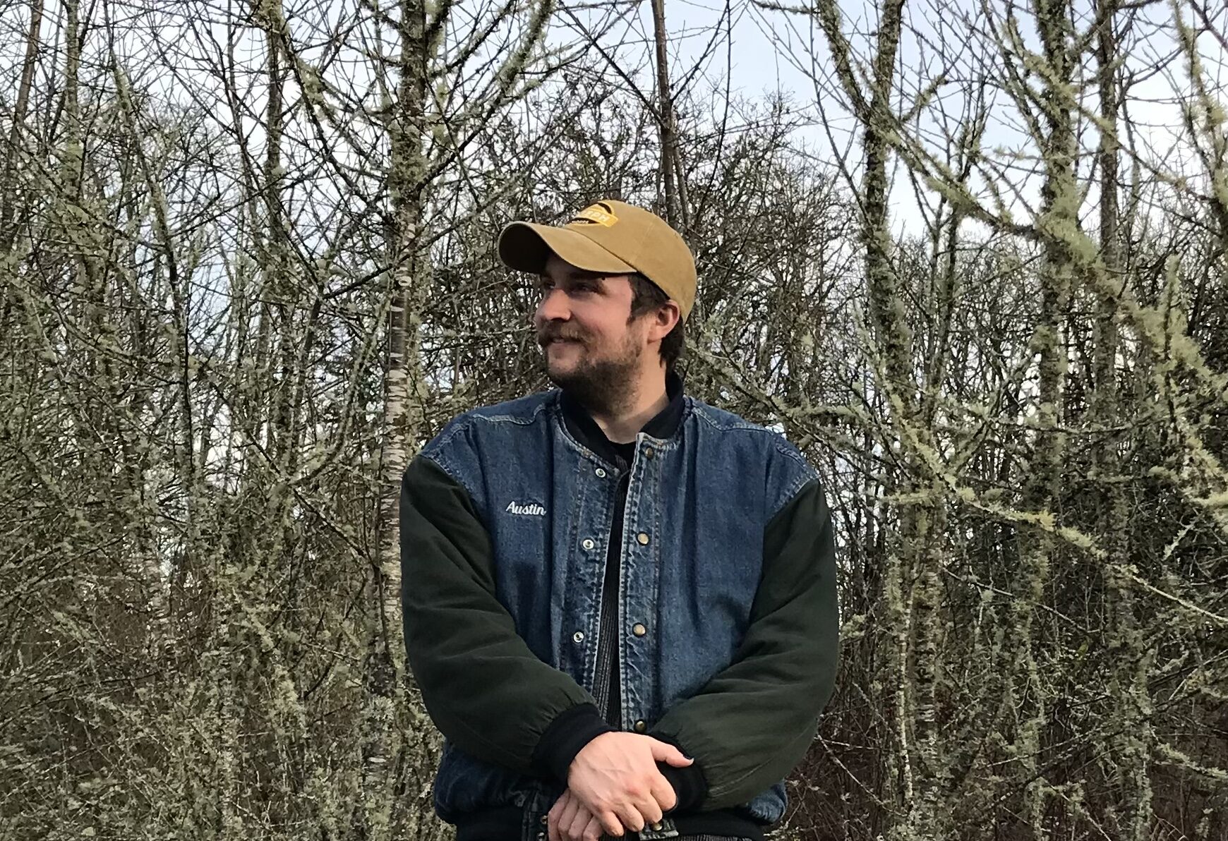 Troy looking into the distance while standing in the woods