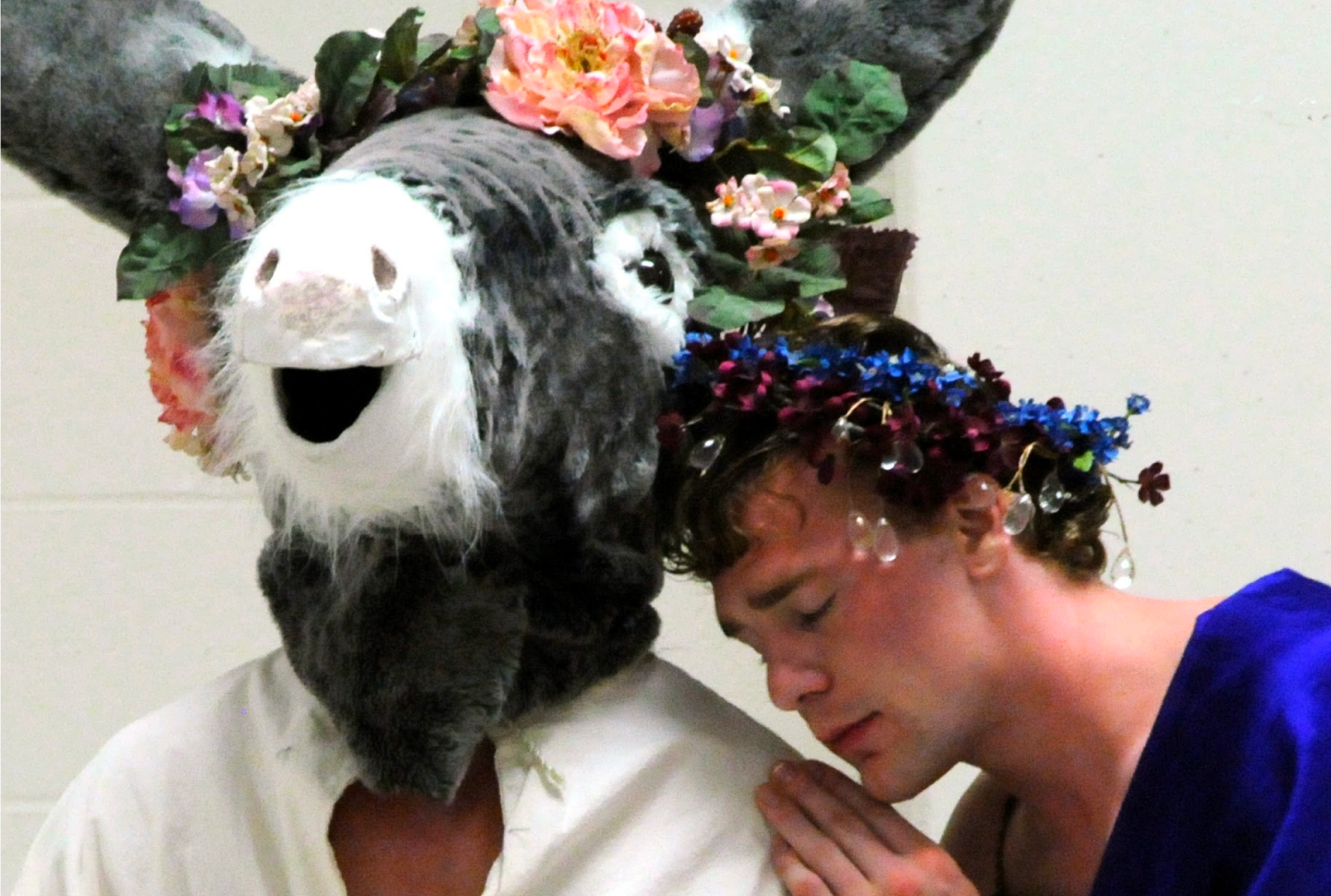 Actors perform A Midsummer Nights dream. Titania rests her head on a Donkey wearing a flower crown.
